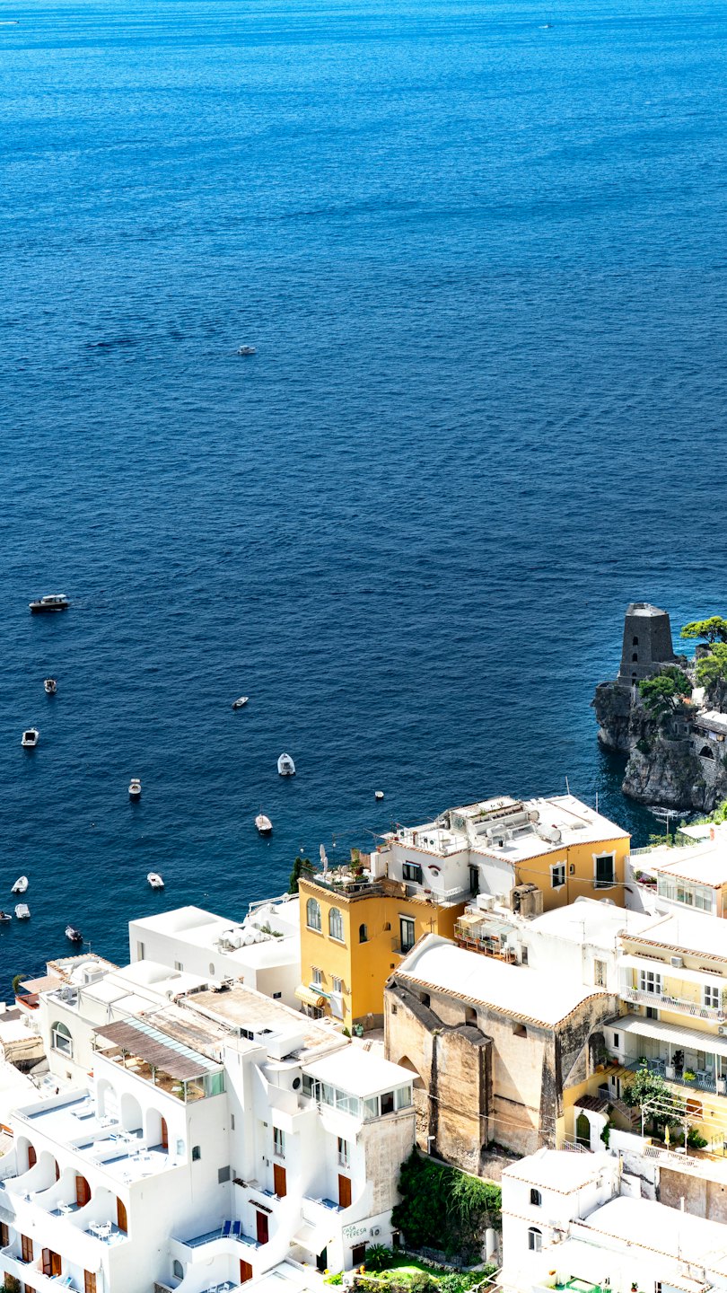 Coastal town with colorful buildings perched above a blue sea.
