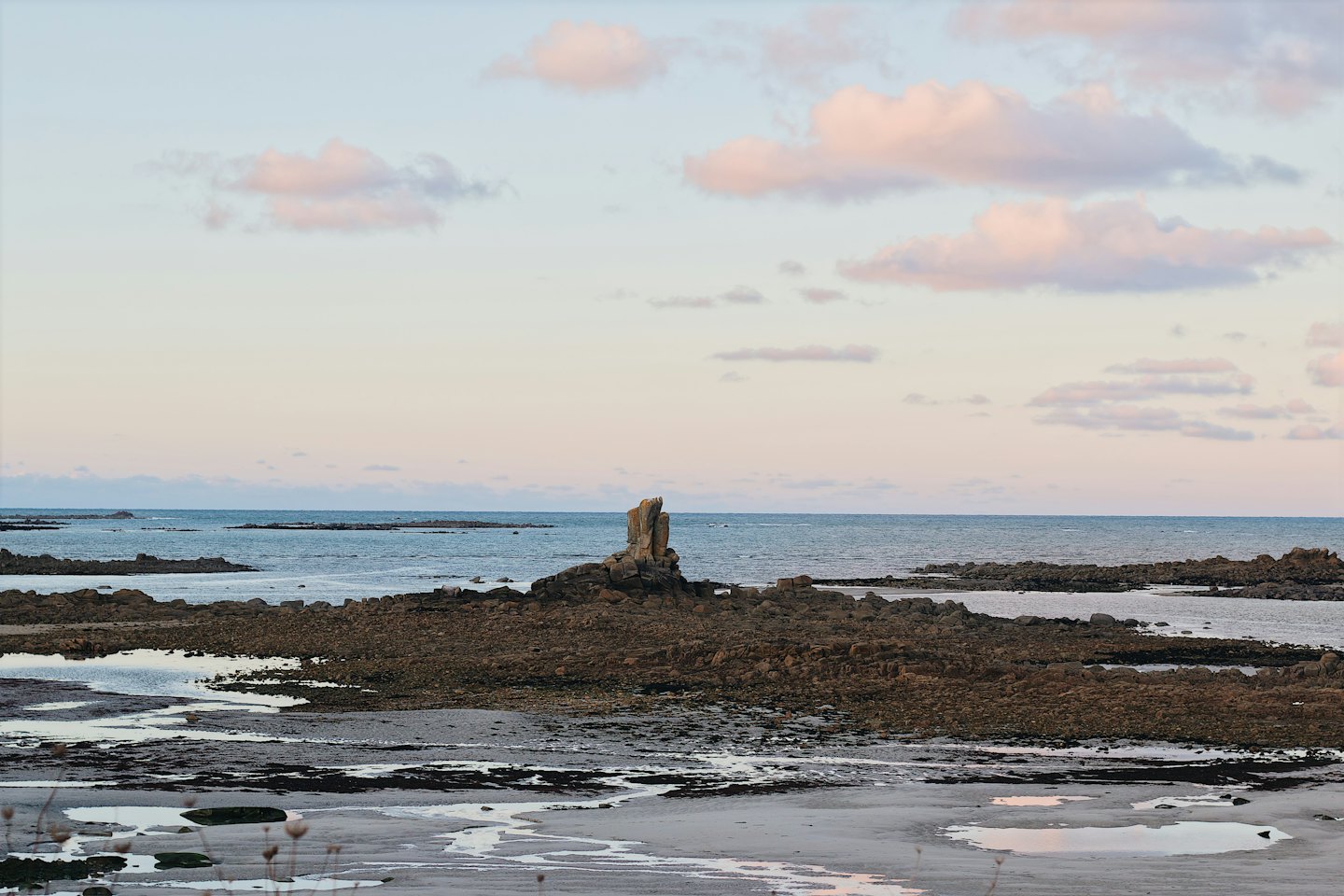 Rocky shore with tidal pools leading to a calm sea.