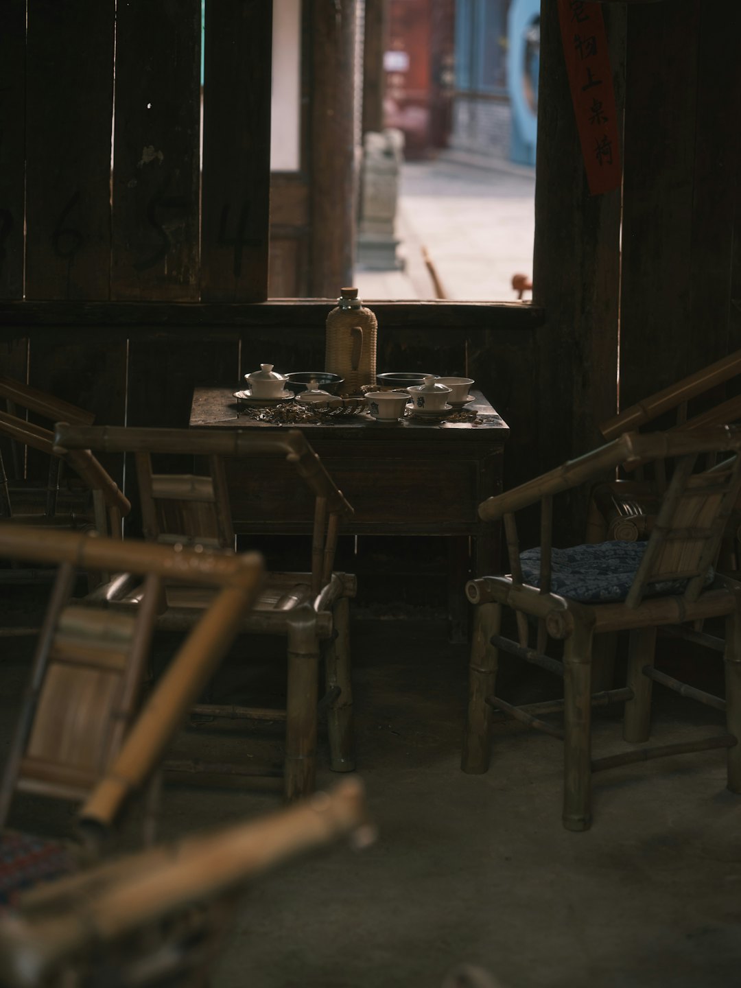 Traditional tea set arranged on a wooden table with bamboo chairs.