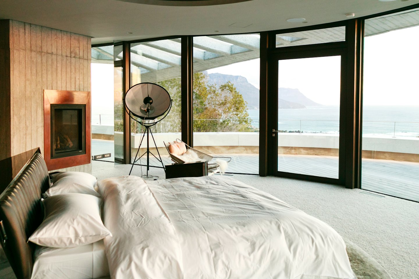 Modern bedroom with ocean view and fireplace.